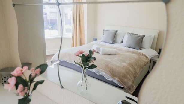 A neatly arranged bedroom with a bed, pillows, a vase with flowers, and a bedside table. - 6-bed House - Sleeps 13 - Families & Contractors (Dudley)