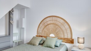 Un dormitorio con cama, mesita de noche, silla, cabecera fijada a la pared y una escalera.