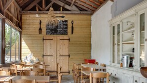 Un interior rústico de madera con mesas y sillas de madera, un menú en una pizarra y un gran armario.