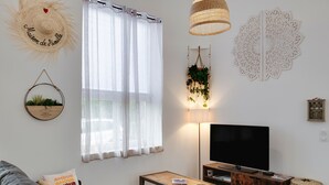 Una sala de estar con sofá, mesa de centro, televisor, lámpara y decoración en la pared.