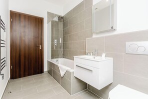 Un baño moderno con puerta de madera, bañera, ducha y tocador blanco.