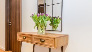 A wooden console table with two drawers, a vase with flowers, and a large mirror on the wall. - Flying Butler Richmond Tersha Street Apartments (Richmond)