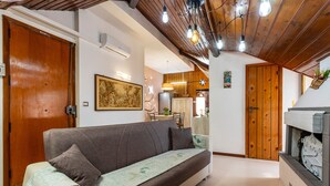 A living room with a sofa, wooden doors, a fireplace, and a dining area in the background. - Apartment 'Reale' with Private Terrace, Wi-Fi and Air Conditioning (Gravina di Catania)