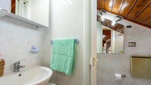 A bathroom with a white sink, a green towel, a mirror, and a toilet. - Apartment 'Reale' with Private Terrace, Wi-Fi and Air Conditioning (Gravina di Catania)