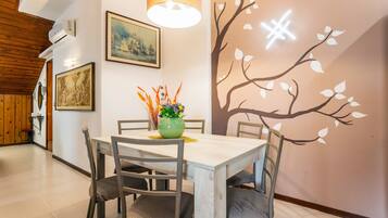A dining area with a table, chairs, a vase with flowers, and wall art.