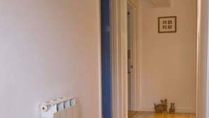 Ein Flur mit einem Heizkörper, einem blauen Türrahmen und einem kleinen Bild in einem Rahmen an der Wand.