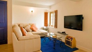 Ein Wohnzimmer mit einer Couch, einem Couchtisch, einem Fernseher und einem Fenster mit Rollläden.
