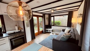 A modern kitchen with a built-in oven, a dining area with a sofa, and large windows offering a view of the outdoors.