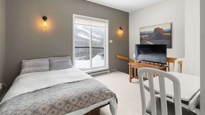 Un dormitorio con cama, televisión, escritorio y silla.