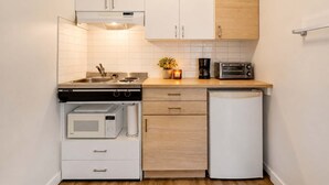 A compact kitchen with white cabinets, a microwave, a coffee maker, and a toaster.