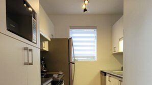 A modern kitchen with built-in appliances, a wooden floor, and a window providing natural light.