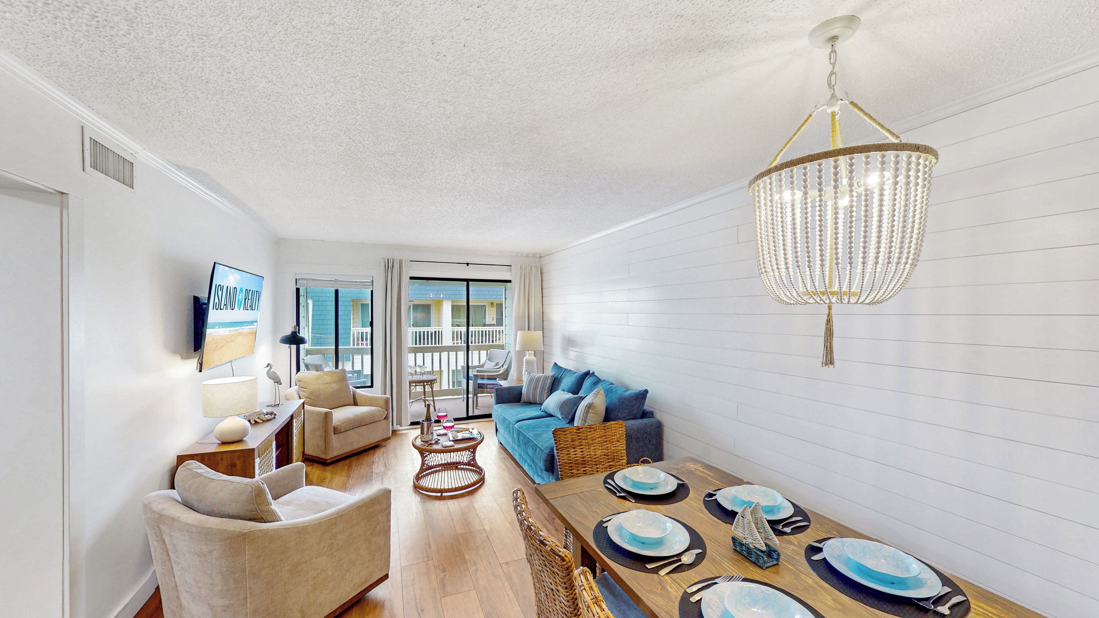 Una sala de estar moderna con un sofá, una mesa de comedor preparada para cuatro personas y una araña.