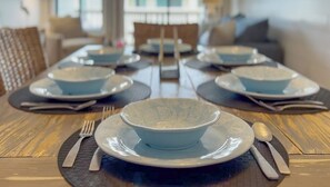 Uma mesa de jantar posta com pratos, tigelas, talheres e jogos americanos.