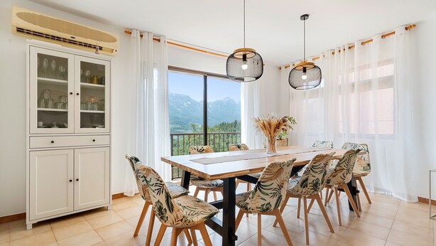 Un espace repas comprenant une grande table, des chaises, un buffet et une vue sur les montagnes.