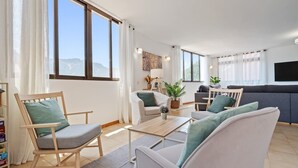 Un salon moderne comprenant un canapé, un fauteuil, une table basse et un téléviseur à écran plat.