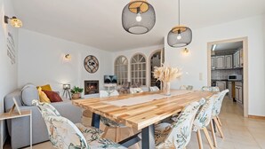 Un salon spacieux avec une table à manger en bois, des chaises à motifs floraux, un canapé gris et une cheminée.