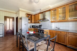 A kitchen with wooden cabinets, a stainless steel range hood, a glass dining table, and a refrigerator. - Villa 'Casa Campo Da Feira' with Private Pool, Private Terrace and Wi-Fi (Várzea)