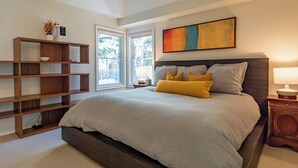 Un dormitorio con una cama grande, una estantería de madera, un cuadro y una ventana con vistas.