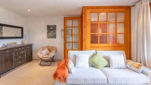 A room with a sofa, a chair, a cabinet, and a large window with frosted glass panels.