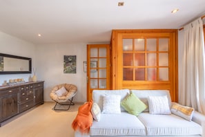 Quarto com sofá, cadeira, armário e uma grande janela com painéis de vidro jateado.