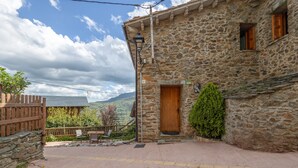 A stone building with a wooden door, a small porch, and a view of the countryside.