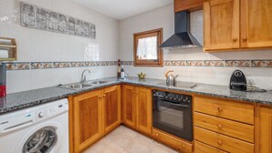 A kitchen with wooden cabinets, a washing machine, a stove, and a sink.
