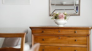 Un aparador de madera con cajones, un florero con flores y un espejo en la pared.