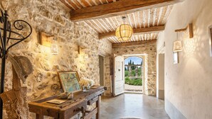 A rustic stone interior with a wooden bench, a painting, and a hanging light fixture.