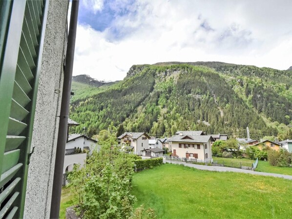 A residential area with houses, a green lawn, and a mountain in the background.