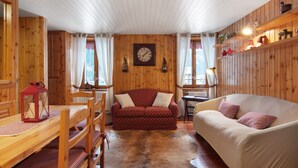 A wooden interior with a red patterned sofa, a white sofa, a wooden table, and a red lantern. - Apartment 'Corti Garden' with Mountain View, Private Garden and Wi-Fi (Campodolcino)