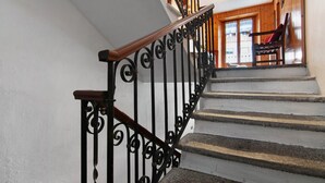 A staircase with black iron railings and wooden handrails, leading to a room with a wooden interior and a window. - Apartment 'Corti Garden' with Mountain View, Private Garden and Wi-Fi (Campodolcino)