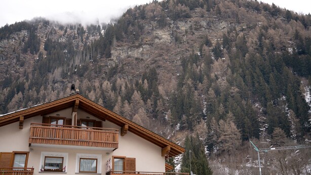 A two-story building with a balcony, set against a mountainous backdrop. - Apartment 'Corti Garden' with Mountain View, Private Garden and Wi-Fi (Campodolcino)