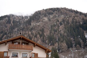 A two-story building with a balcony, set against a mountainous backdrop.