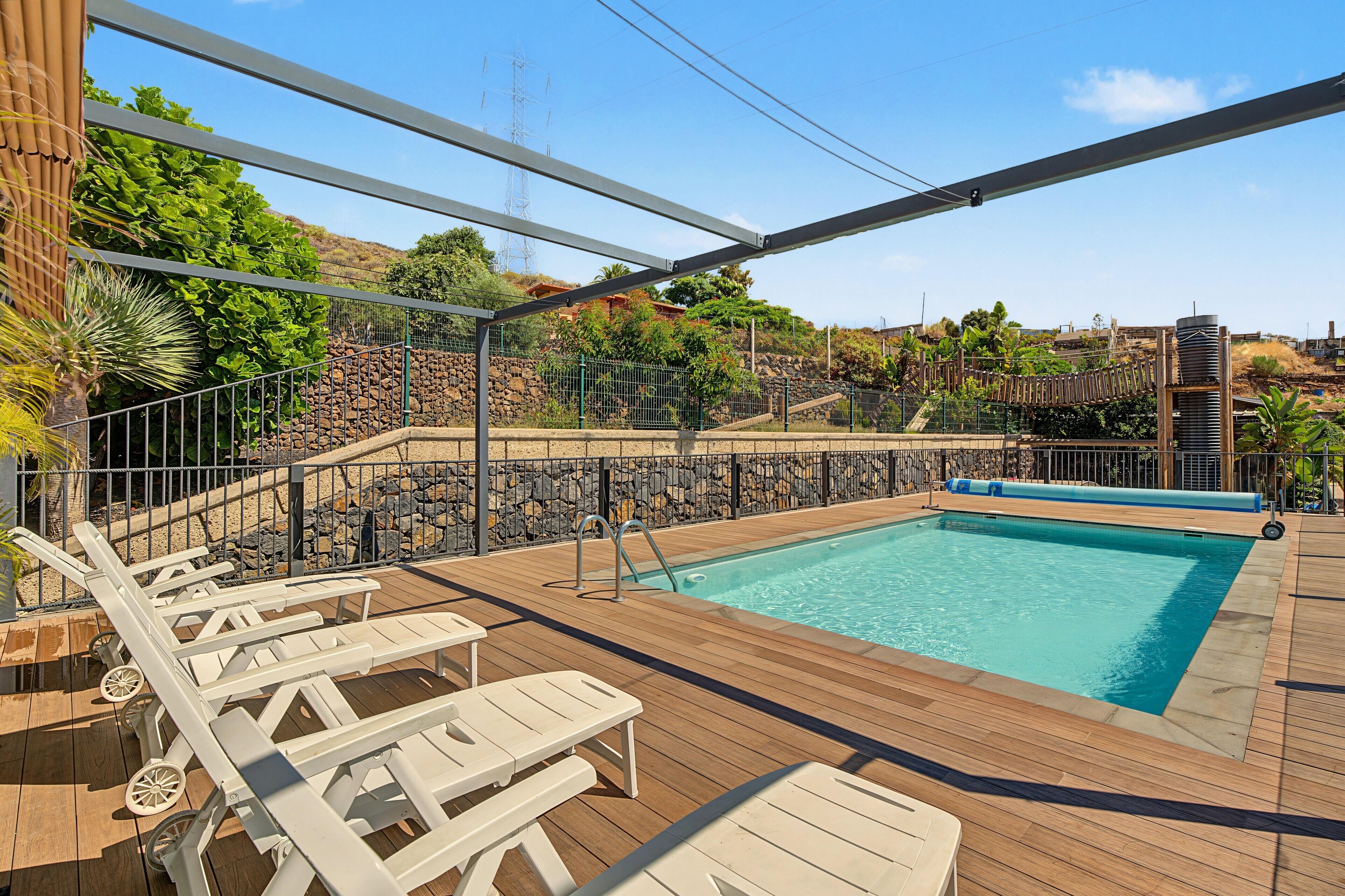 Un espace piscine avec des chaises longues et une vue sur une colline.