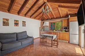 A cozy kitchen with wooden beams, a dining table, and a sofa. - 'Finca Verónica' with Sea View, Wi-Fi and Air Conditioning (Candelaria)
