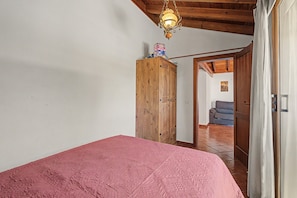 A bedroom with a wooden wardrobe, a bed with a pink bedspread, and a hallway leading to another room. - 'Finca Verónica' with Sea View, Wi-Fi and Air Conditioning (Candelaria)