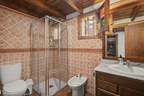 Un baño con ducha, inodoro, bidé y lavamanos con espejo.
