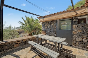 A stone building with a tiled roof, a window, and a table with benches. - 'Finca Verónica' with Sea View, Wi-Fi and Air Conditioning (Candelaria)