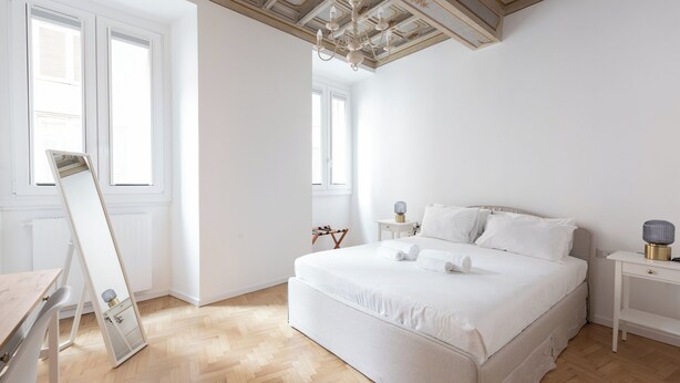 A bedroom with a large bed, a nightstand, a mirror, and a window. - City Center- Modern and Bright apartment (Rome)