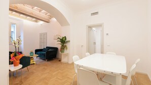 A modern living room with a white table and chairs, a dark sofa, and a potted plant. - City Center- Modern and Bright apartment (Rome)