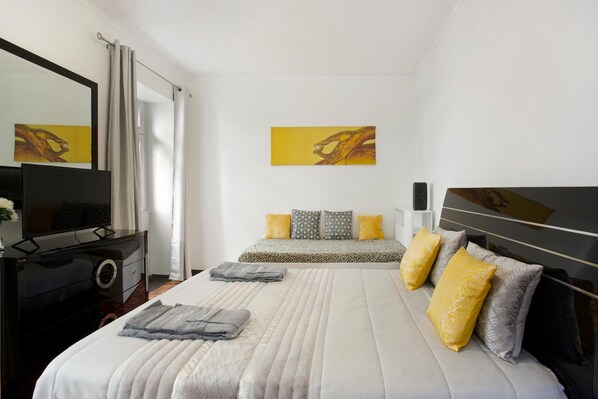 A bedroom with a bed, a TV, a dresser, and artwork on the walls.