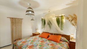 Un dormitorio con cama, mesita de noche, planta colgante, dosel y lámpara de techo.