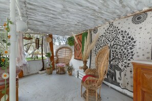 Una habitación con una silla de fibras naturales, un tapiz en la pared y una planta en maceta.