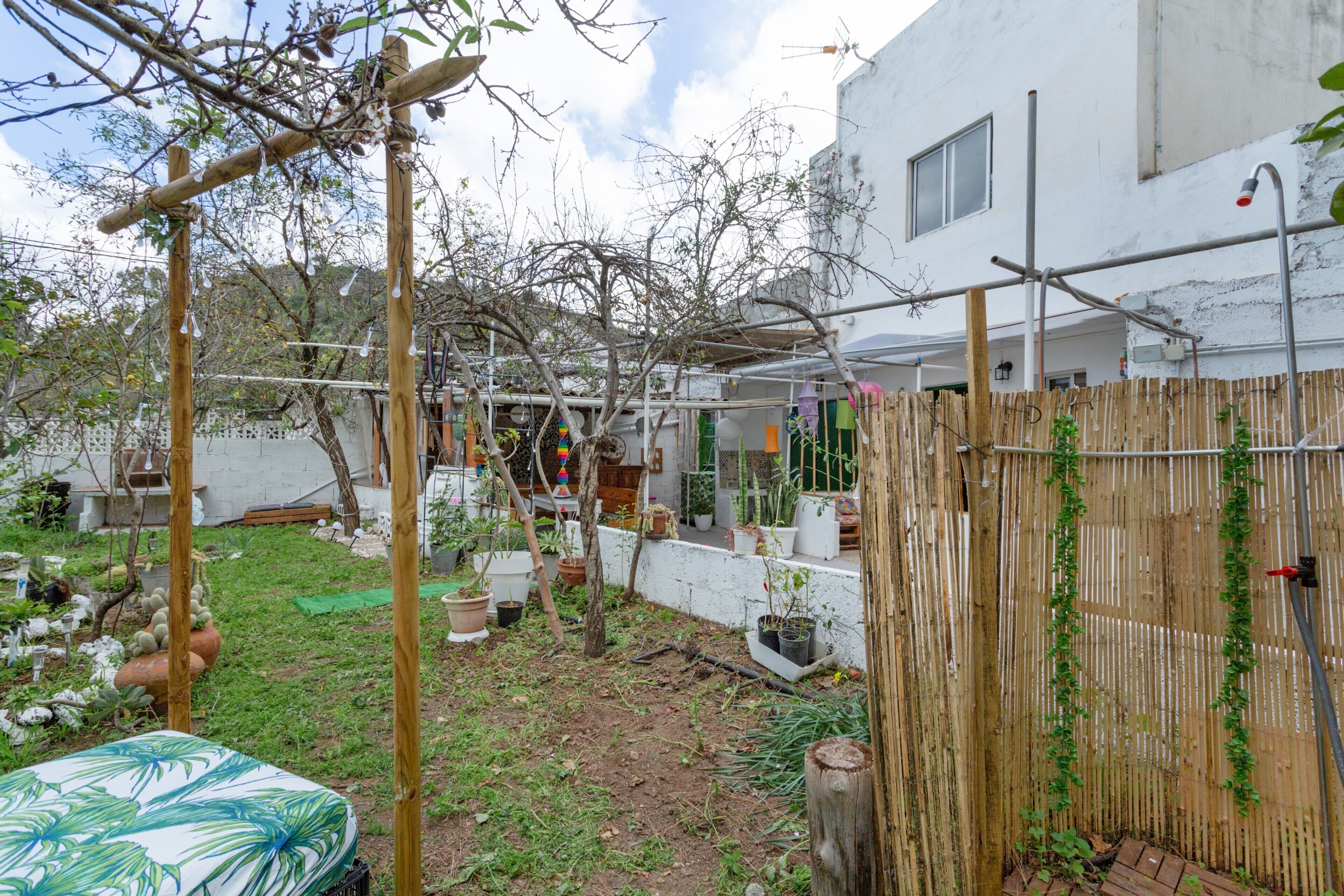 Un jardin agrémenté d’une pergola en bois, de plantes en pot et d’une clôture en bambou.