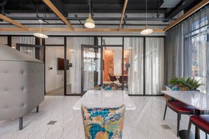 A modern office space with a large meeting table, comfortable seating, and a view of the city through large windows.