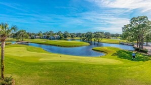 Un parcours de golf agrémenté d’obstacles d’eau, d’un pont et d’un green bien entretenu.