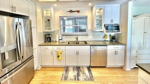 Une cuisine moderne dotée d’appareils électroménagers en acier inoxydable, de meubles blancs et d’un plancher en bois.
