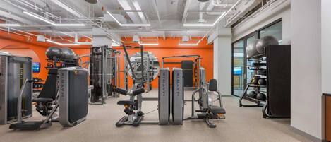 A gym with various exercise equipment, including treadmills, weight machines, and a rack of dumbbells.