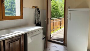 A kitchen with a dishwasher, a window, and a door leading to a balcony with a wooden fence. - CHARMING CHALET - SLEEPS 6 (Allemont)