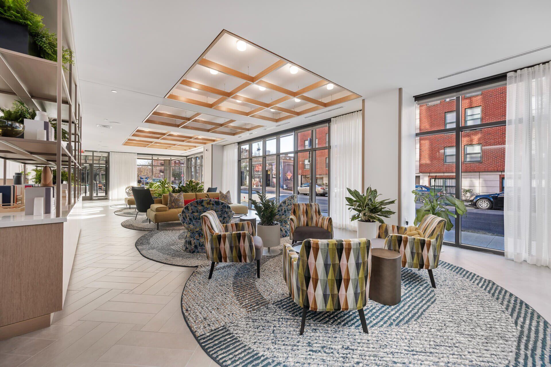A spacious lobby with a high ceiling, large windows, and a variety of seating arrangements.